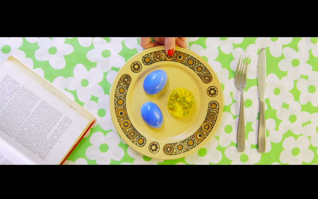 Still image from the film G_iRL. Photo from above of two blue eggs on a yellow plate.